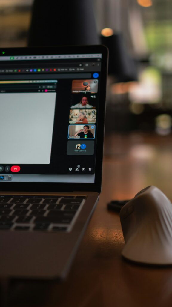 Laptop zeigt eine Videokonferenz mit mehreren Teilnehmenden in einem hybriden Meeting
