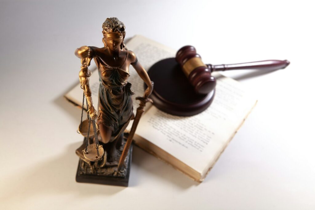 Justitia-Statue, Richterhammer und Gesetzbuch als Symbol für Geschäftsführerhaftung