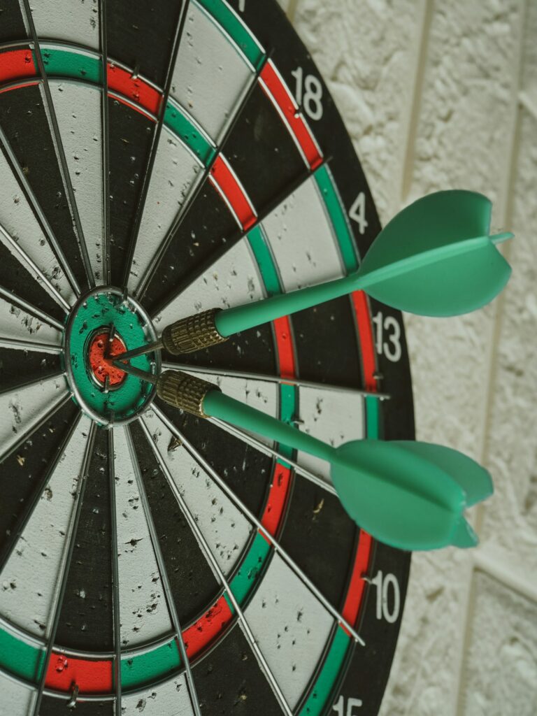 Darts im Zentrum einer Dartscheibe als Sinnbild für ambitionierte OKR-Ziele